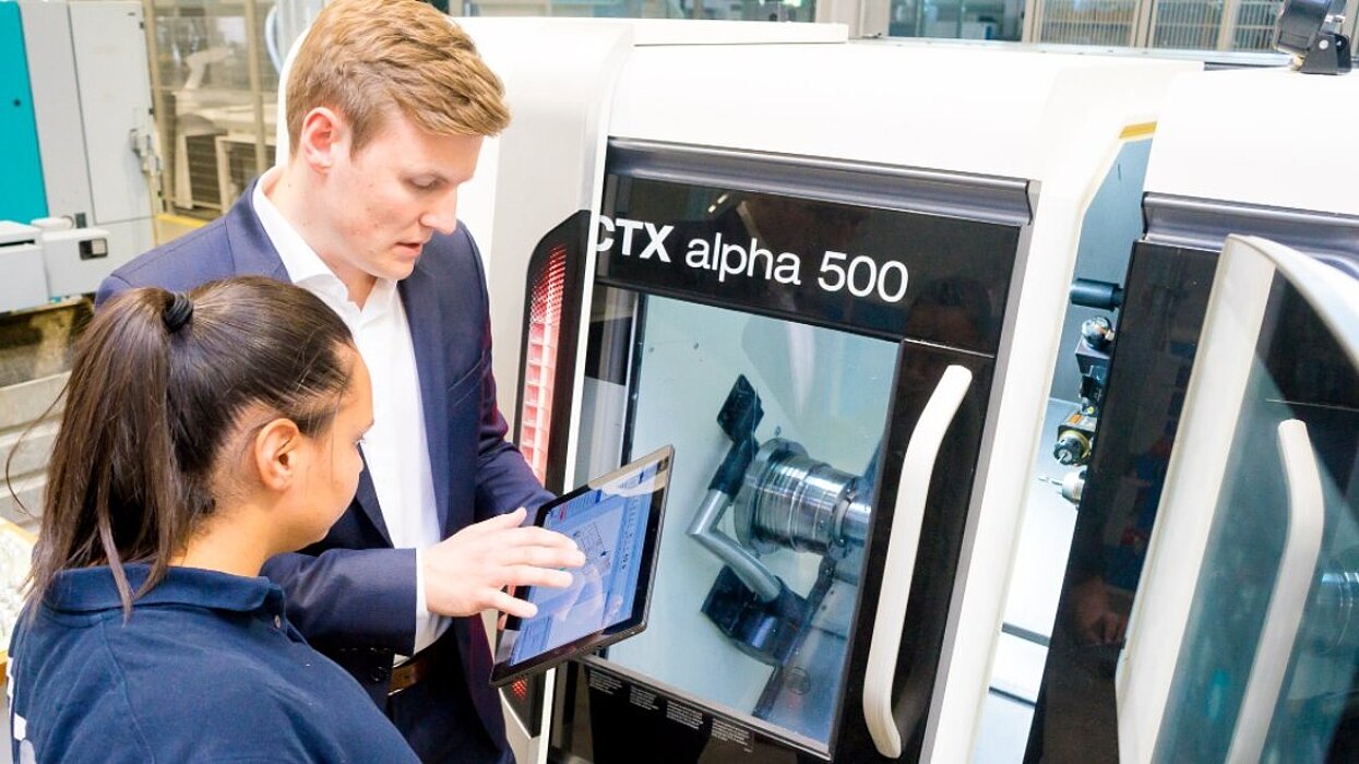 Zwei Personen arbeiten an Produktionsmaschine