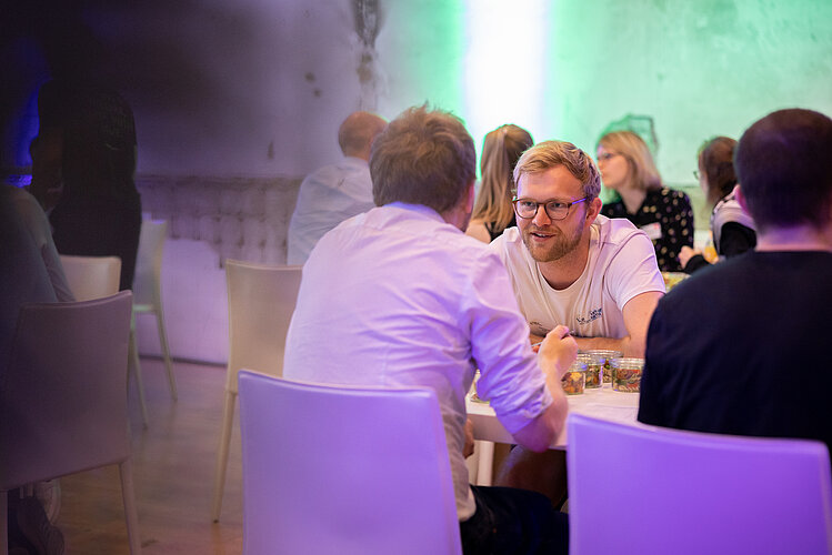 Technologietransfer Personen sitzen an einem Tisch und tauschen sich aus.